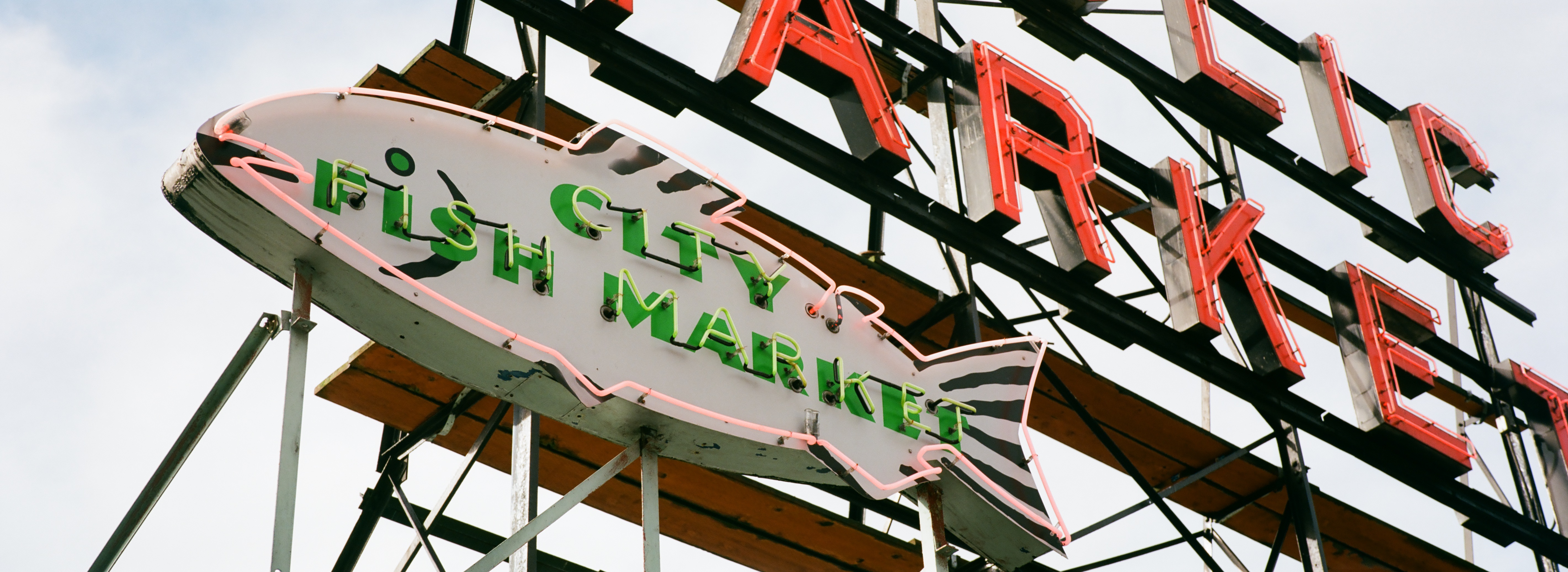 A close up of a neon sign at Pike Place Public Market, in the shape of a salmon with inlaid text which reads City Fish Market.